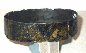Das punzverzierte Armband aus Bronzeblech wurde am linken Unterarm gefunden; Dm.: 67-71 mm